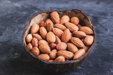 Almonds in coconut shells on a dark background