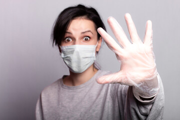 beautiful woman in medical mask and gloves shows stop hand, protection against virus