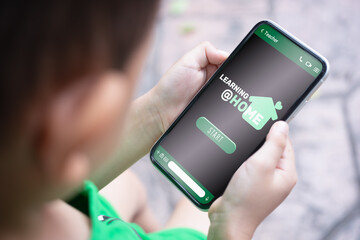 Learning at home for quarantine times in Coronavirus Covid-19 pandemic outbreak background new normal distant learning concept. Child holding mockup mobile phone with e-larning application.