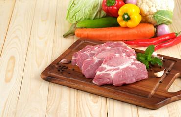 Pork neck Slice on wooden plate on wooden table with vegetables on background
