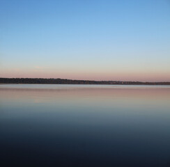 The horizon line where the surface of the lake passes into the twilight sky