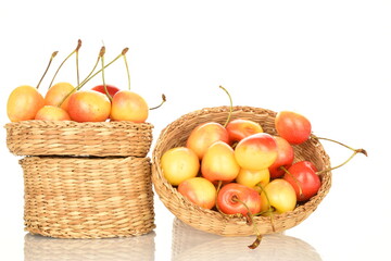 Yellow cherries in a straw bowl, close-up, on a white background.