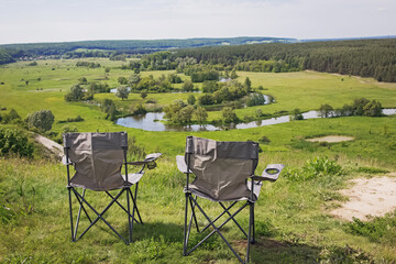 Two camping chairs standing on a hill with a beautiful view
