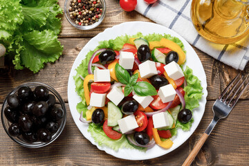 Greek salad with cheese and fresh vegetables on wooden background.