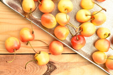 Yellow sweet cherry, close-up, on a metal tray, on a wooden table.
