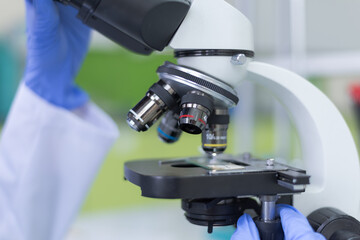 Young female Laboratory scientist working at lab with test tubes and microscope, test or research in clinical laboratory.Science, chemistry, biology, medicine and people concept.