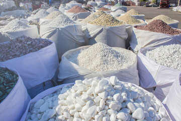 decorative river stones in a big bag outside on the street in factory or decorative stone shop for garden and building, close up macro, copy space for text. Landscaping construction concept