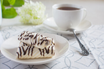 White ceramic cup with tea and cookies in the glaze of white chocolate.