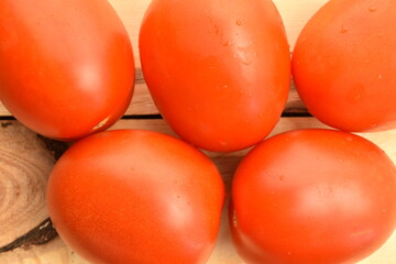 Red plum-like tomato, close-up, on a wooden table.