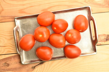 Red plum-like tomato, close-up, on a metal tray.
