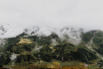 High mountain covered with deep white clouds with small spots of sunrays