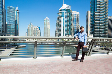 European tourist looks at the views of Dubai. A tourist stands on a bridge over water canal in Dubai.