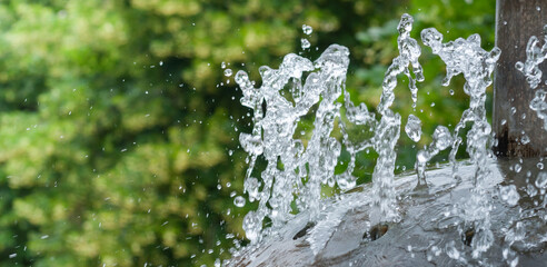 Water gurgling from a street fountain. A splash of water in a fountain, an abstract image. © Maks_Lab
