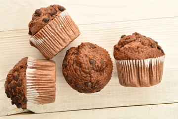 Chocolate muffins on a white wooden table, close-up.