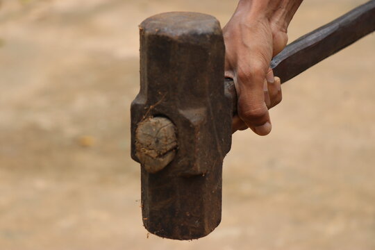 Big hammer which is old and rusty with wooden handle held in hand