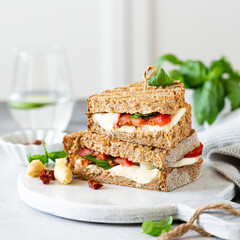 Delicious toast with white asparagus, tomatoes, mozzarella, sun-dried tomatoes and basil on white marble board. Healthy food concept with copy space.