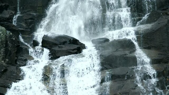 Slow motion footage of waterfall moving in reverse. Water falling in reverse over black stones. Nature concept. Surrealist concept.