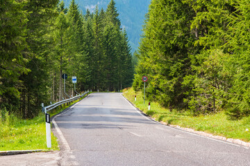 Obraz premium Mountain road in the forests of Dolomites on a sunny day