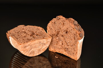 Halved chocolate muffin, close-up, on a black background.