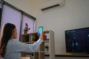 A young woman is using a smartphone with a controlled application. Smart home concept.