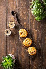 Fototapeta na wymiar Fresh pastry sweet swirl buns with raisins on wooden board for breakfast or brunch and coffee. Top view, copy space.