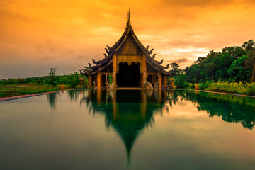 Naklejka premium The background of the Wat Pa Kham Charoen is a beautiful old church with a Buddhist statue and a tree-lined temple, with tourists and travelers always making merit in Udon Thani, Thailand.