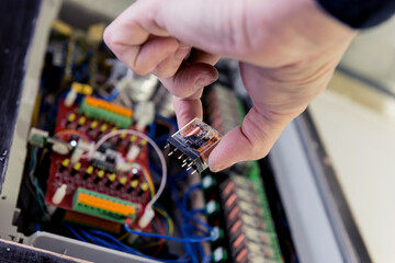 The man is repairing the switchboard voltage with automatic switches.