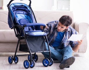 Young father assembling baby pram at home