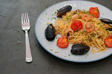 Spaghetti pasta with shrimp, mussels, tomatoes and cheese, copy space. Very tasty and high-calorie, traditional Italian food