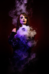 Portrait of a pretty witch with bloody eyes, surrounded by smoke, holding a chalice in her hands