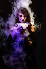 Portrait of a pretty witch with bloody eyes, surrounded by smoke, holding a chalice in her hands