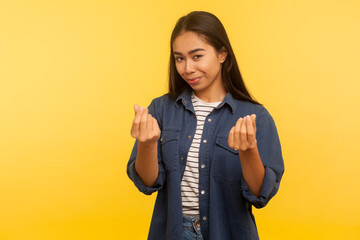 Portrait of greedy girl in denim shirt showing money gesture and looking with cunning smile,...