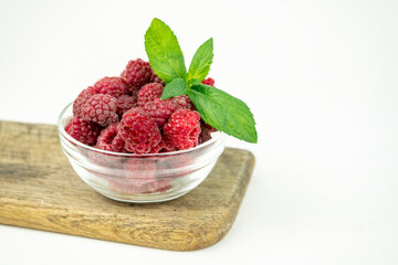 fresh ripe raspberry in a glass transparent bowl on white background