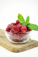 fresh ripe raspberry in a glass transparent bowl on white background
