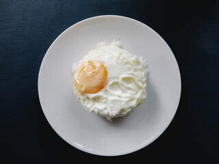 Crispy fried egg Put on steamed rice in a white dish Ready to eat for breakfast, Placed on a blue leather table