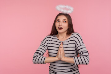 I'm saint angel! Portrait of lovely kind modest woman with holy nimbus over head holding hands in...
