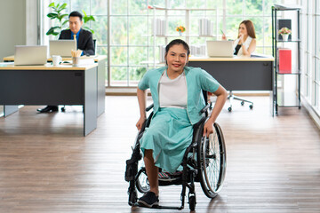 young asian disabled woman with smiling face sitting in the wheelchair and her colleagues sitting...