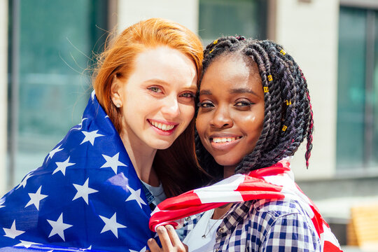 latin hispanic and redhaired ginger women holding usa flag in the street