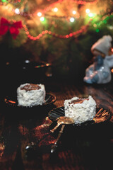 Christmas cake with chocolate and coconut flakes. Fire tree lights and magic atmosphere. Happy holiday!