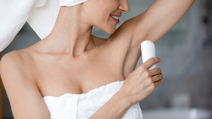 Close up of smiling young woman use deodorant for armpit after shower or bathroom, happy millennial...