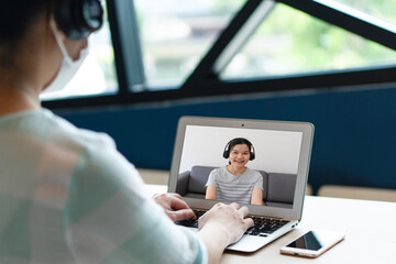 Asian business woman using computer to work from home via video conference with clients during covid-19 or coronavirus outbreak. technology and new normal lifestyle concept