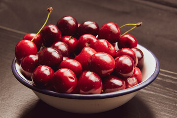 Frisch gepflückte rote Kirschen vor schwarzem Hintergrund als Studioaufnahme.