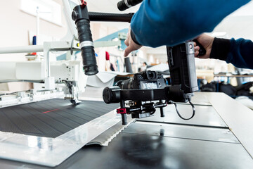 Videographer using stadicam, making video of machine at sew factory