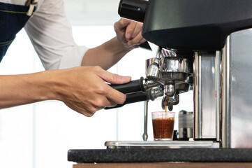 close up picture of coffee maker machine brewing expresso into a cup in the restaurant. barista and coffee shop concept