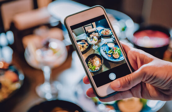 woman hand with smartphone photographing food at restaurant or cafe