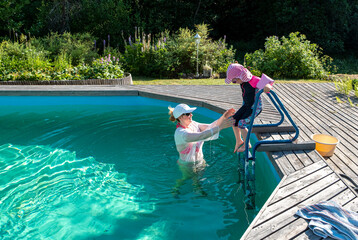 Swimming in the pool. A family of Caucasians, a girl and a child swimming in the outdoor pool.