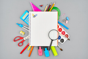 Colored stationery, watercolors, compasses, markers, pencils, and a calculator are covered with an...