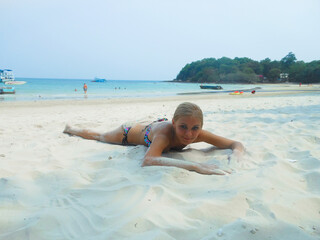 young tanned slim woman in a swimsuit is lying on the sand on the beach. the ocean behind, thailand, tanning, vacation