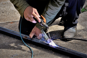 A chama da solda da barra de ferro no chão