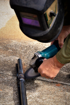 Serralheiro serrando com a m&aacute;quina o ferro no ch&atilde;o